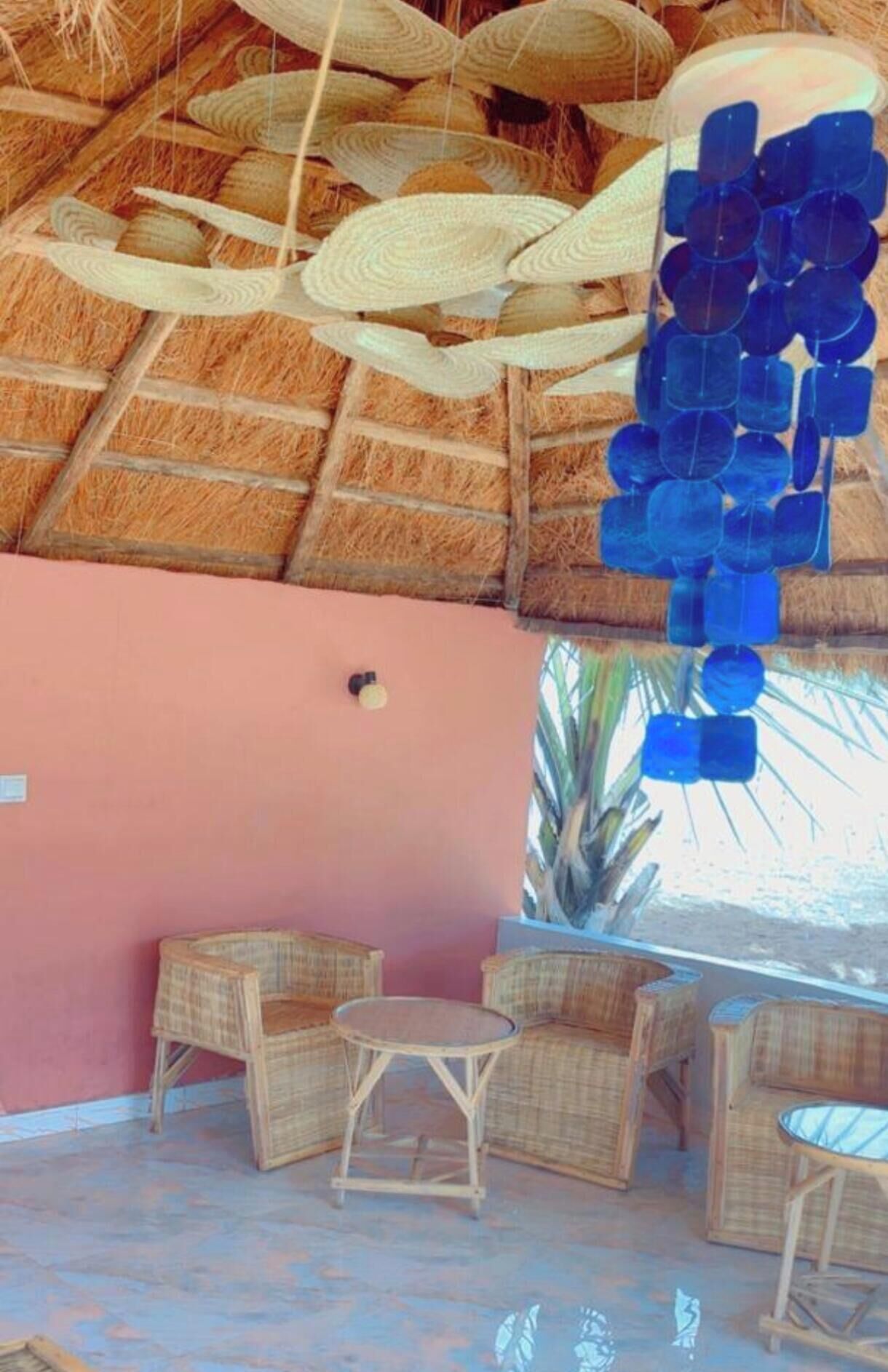 A room with a thatched roof, wicker furniture, and a pink wall.