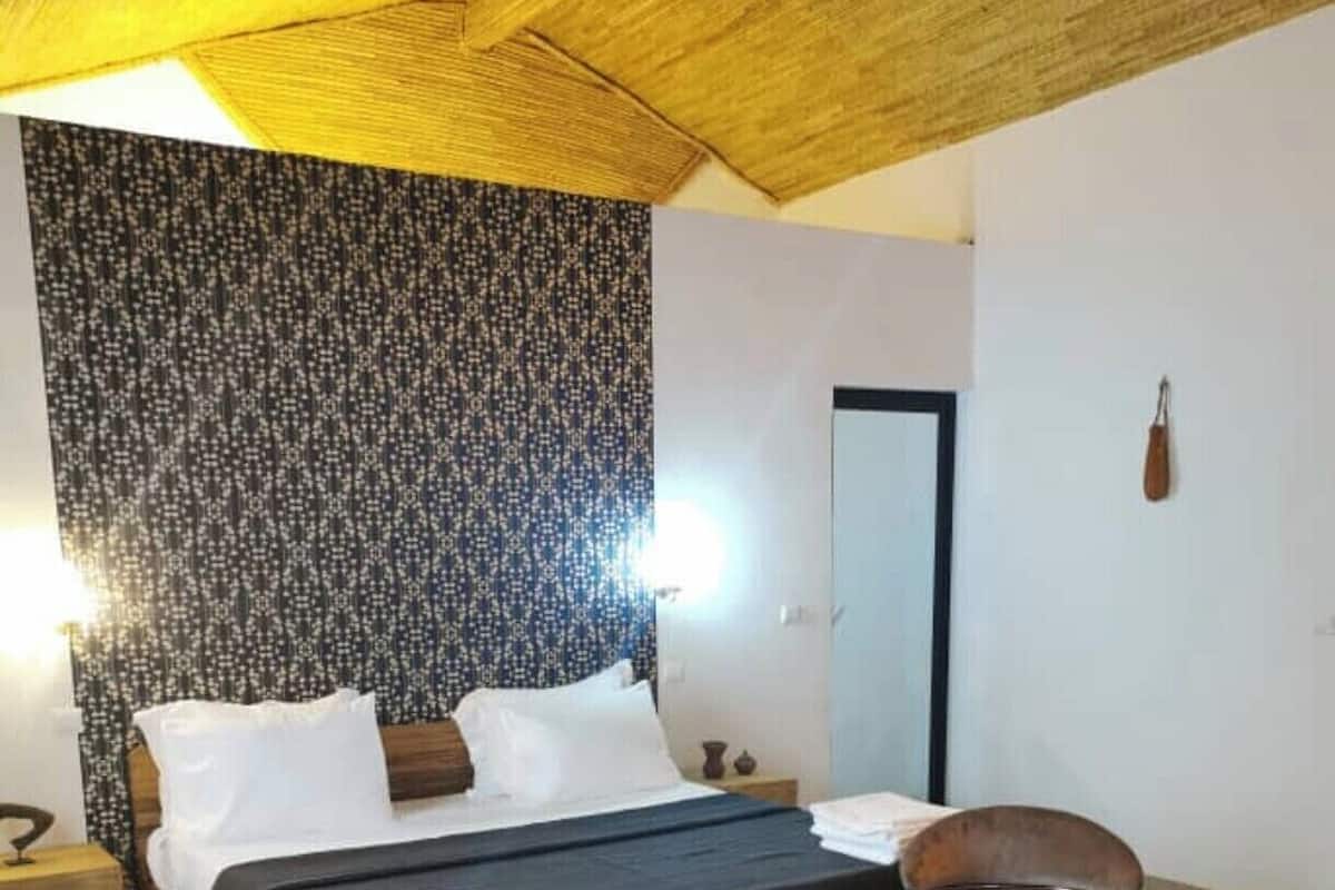 A bedroom with a bed, two chairs, a small table, and a nightstand.