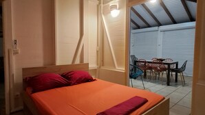 Ein Schlafzimmer mit einem hölzernen Bett, roter Bettwäsche und einem Deckenventilator.