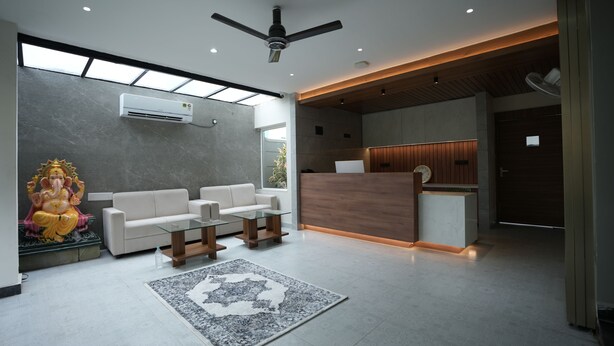 A modern reception area with a reception desk, seating area, and a ceiling fan. - AANGAN INN (Bhubaneshwar)