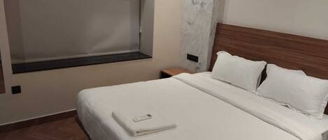 Habitación de hotel con cama, mesita de noche, ventana y pared de mármol.