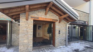 A building entrance with a stone facade, wooden beams, and a glass door. - Parenthèses A12 by Avecoeur (Huez)