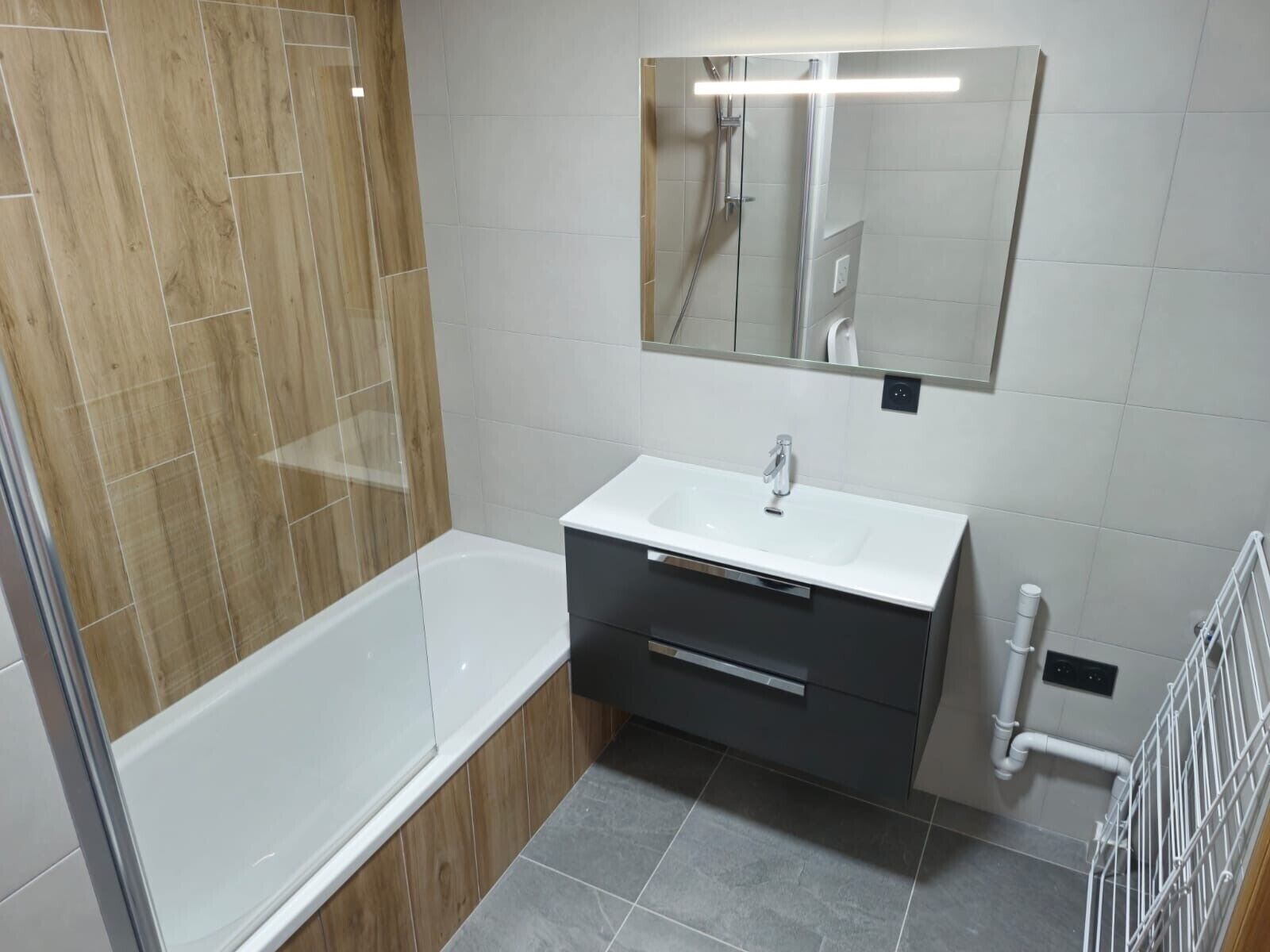 Un baño moderno con bañera, tocador con espejo y zona de ducha.
