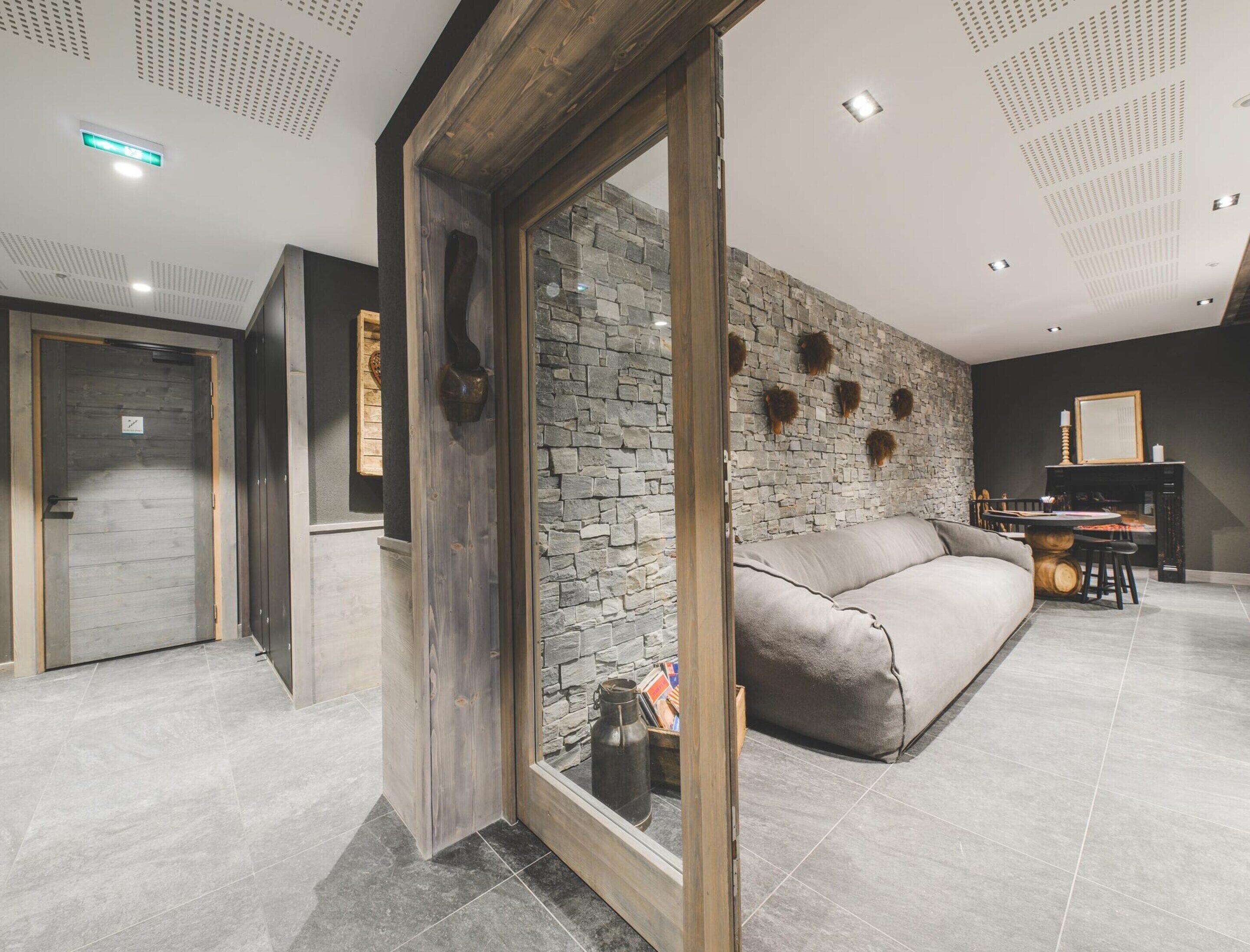 A modern living room with a stone wall, a sofa, and a wooden door.