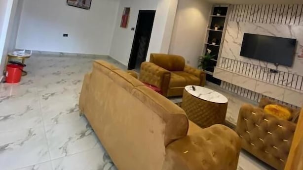 Amplia sala de estar con un sofá beige grande, una mesa de centro redonda y un televisor montado en la pared.