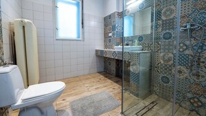 A bathroom with a toilet, a shower with patterned tiles, and a window. - Trzy Kafki (Kraków)