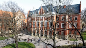 A historic building with a central courtyard, surrounded by trees and a paved walkway. - Trzy Kafki (Kraków)