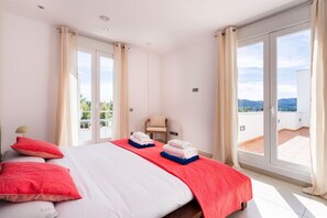 Quarto com cama, uma cadeira e vista para o exterior.