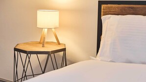 Un lit bien fait, avec du linge de lit blanc et une tête de lit en bois.