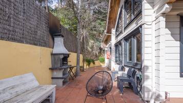 Un patio con un banco de madera, una silla de metal y una parrilla.