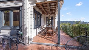 Une terrasse couverte avec une table et des chaises, un vélo et une vue sur le paysage.