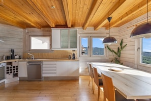 Una cucina moderna con mobili in legno, lavastoviglie integrata e una grande isola con posti a sedere.
