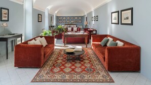 A spacious living room with a red velvet sofa set, a patterned rug, and a dining area with a table and chairs. - Prestigious villa with private pool in Chiaramonte Gulfi - DiCasaInSicilia (Chiaramonte Gulfi)