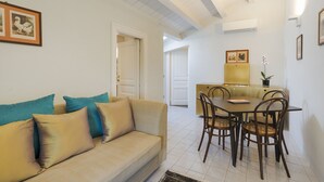 Un soggiorno con divano, un tavolo da pranzo con sedie e una zona cucina sullo sfondo.