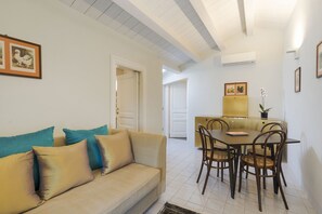 Una sala de estar con sofá, una mesa de comedor con sillas y una cocina al fondo.