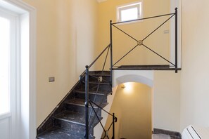 Un escalier doté d’une rampe métallique et d’un luminaire placé au-dessus.