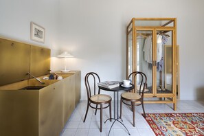 Une pièce de taille modeste, avec un meuble en bois, une petite table et deux chaises, un miroir et un tapis à motifs.