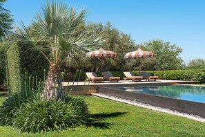 Un espace aménagé au bord de la piscine, avec des chaises longues et des parasols à rayures.