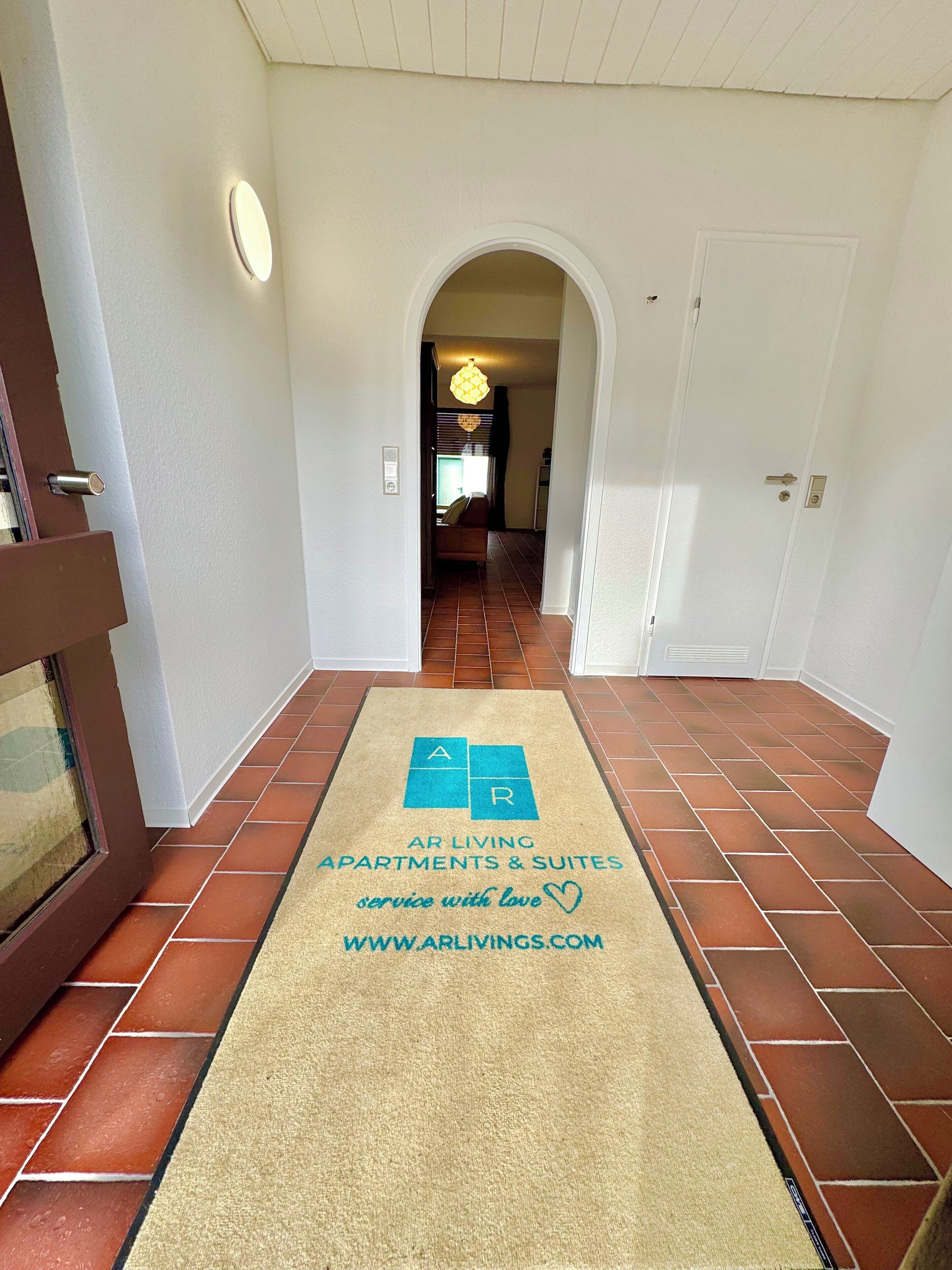 A hallway with a doormat that reads "AR LIVING APARTMENTS & SUITES service with love www.arliving.com".