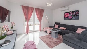 A modern living room with a grey sofa, a coffee table, and pink curtains. - Villa Jana 1 (Novalja)