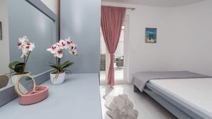 A bedroom with a bed, a mirror, and two potted orchids. - Villa Jana 1 (Novalja)