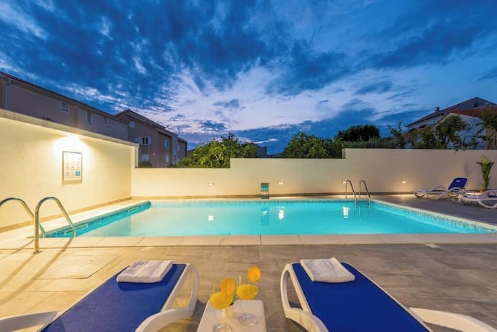 A swimming pool with lounge chairs and a small table with flowers.