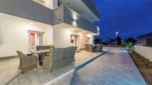 A modern outdoor patio area with a dining table and chairs, a sofa, and a car parked nearby. - Villa Jana 1 (Novalja)