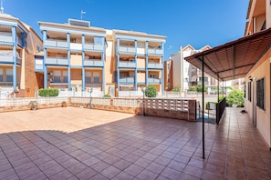 Un immeuble rĂ©sidentiel Ă plusieurs Ă©tages, dotĂ© de balcons, dâun patio couvert et dâune cour dallĂ©e.