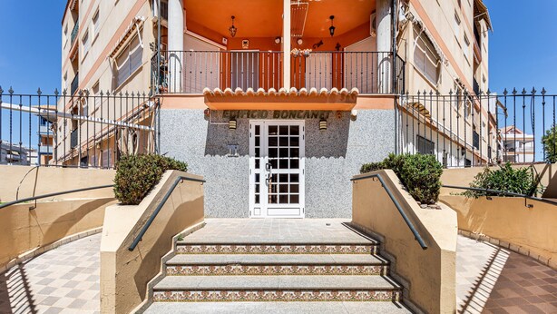 Un bâtiment doté d’une entrée centrale, d’un escalier menant à un balcon et d’une clôture qui l’entoure.