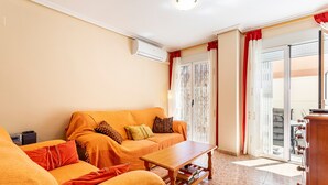 Un salon comprenant un canapé, une table basse et une porte-fenêtre coulissante donnant sur un balcon.