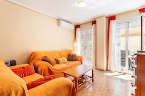 Ein Wohnzimmer mit einer Sofagarnitur, einem Couchtisch und einer Schiebetür zum Balkon.