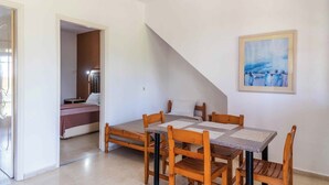 A room with a dining table and chairs, a bed with a pink bedspread, and a painting on the wall. - Pink House Socrates Corfu Courtyard Apartment (Corfu)