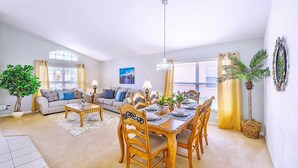 A spacious living room with a dining area, featuring a wooden dining table, chairs, and a sofa set. - Family Resort Home w Pool BBQ Game Room (Davenport)