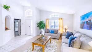 A spacious living room with a sofa, a coffee table, and a large window with curtains. - Family Resort Home w Pool BBQ Game Room (Davenport)