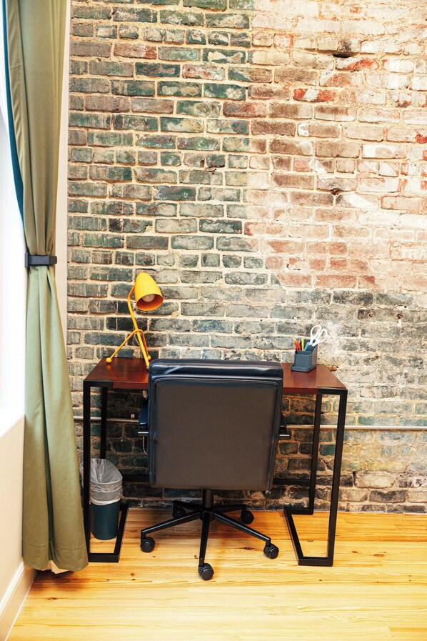 A corner workspace with a desk, chair, lamp, and a brick wall. - Loft 308 The William Views Over Carrigan s (Birmingham)