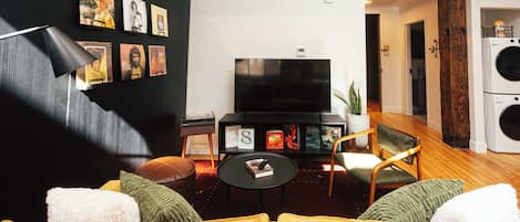 A living room with a sofa, a coffee table, a TV, and a bookshelf.