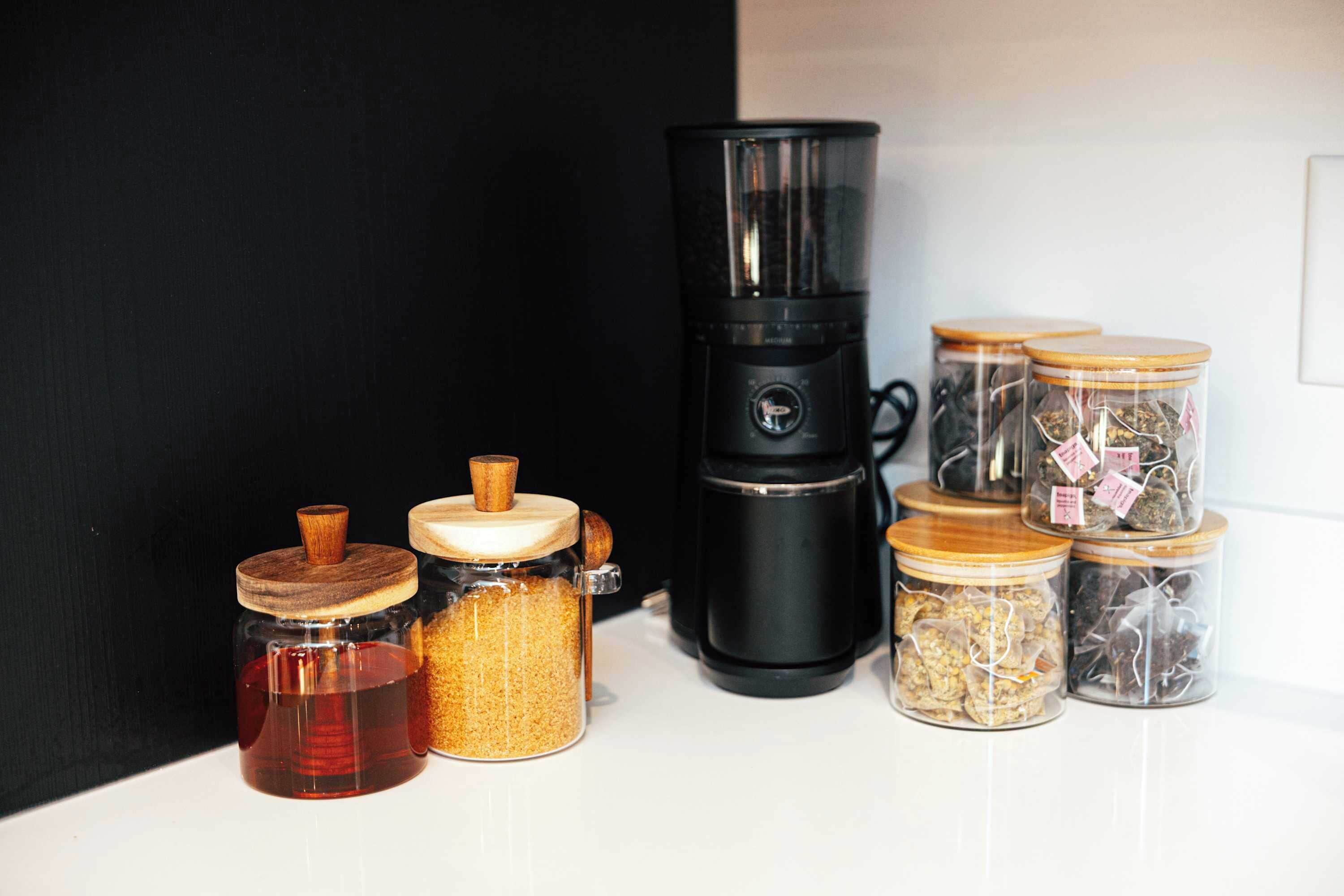 Eine Küchenarbeitsplatte mit verschiedenen Gläsern, die unterschiedliche Lebensmittel enthalten, und einer schwarzen Kaffeemaschine.
