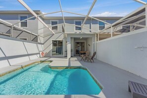Piscina com teto de vidro, área de refeições e vista para um edifício.