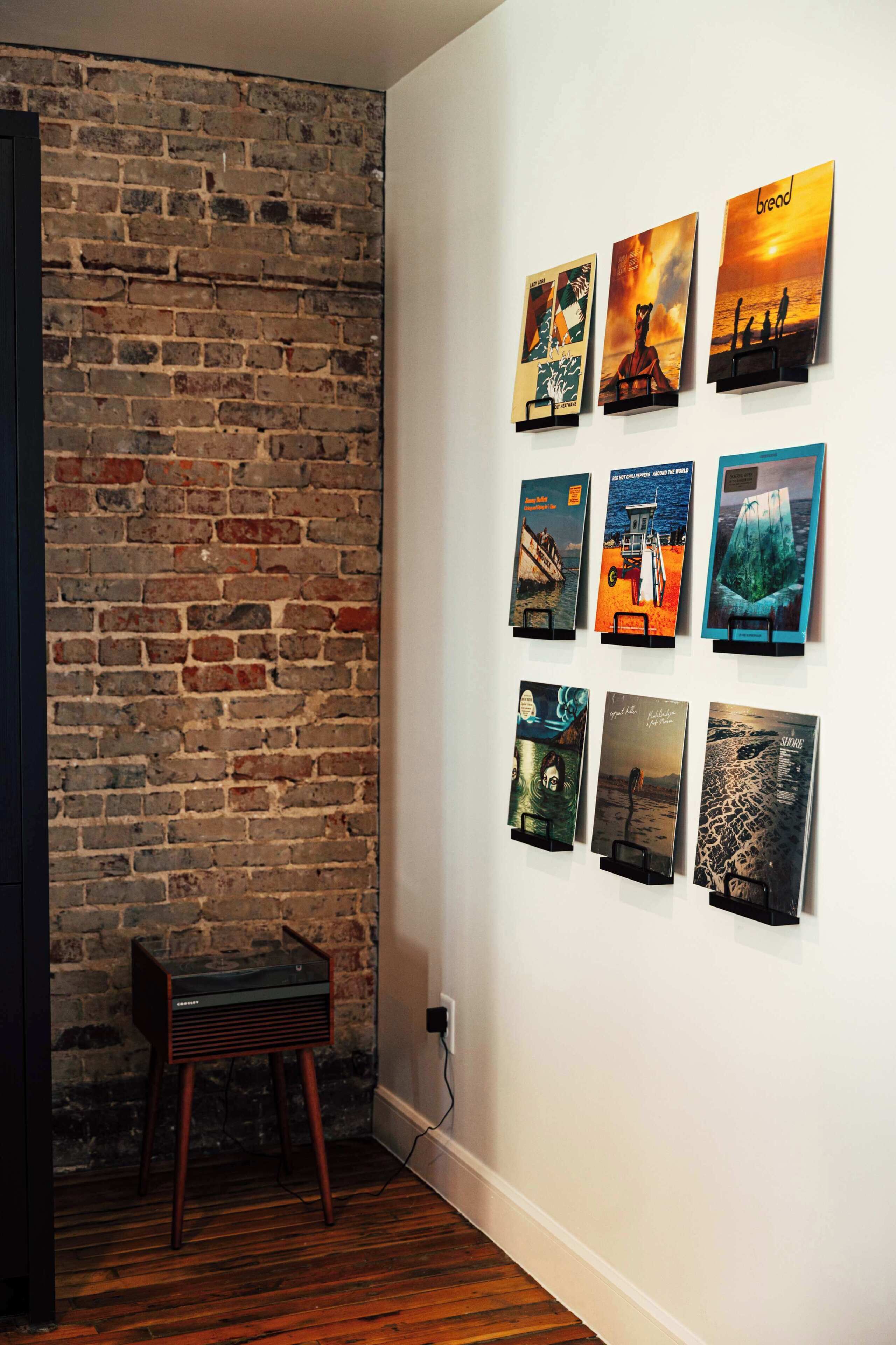 A room with a brick wall, wooden flooring, and a wall-mounted art display.