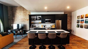 Una cucina moderna con isola centrale, sgabelli da bar e parete in mattoni.