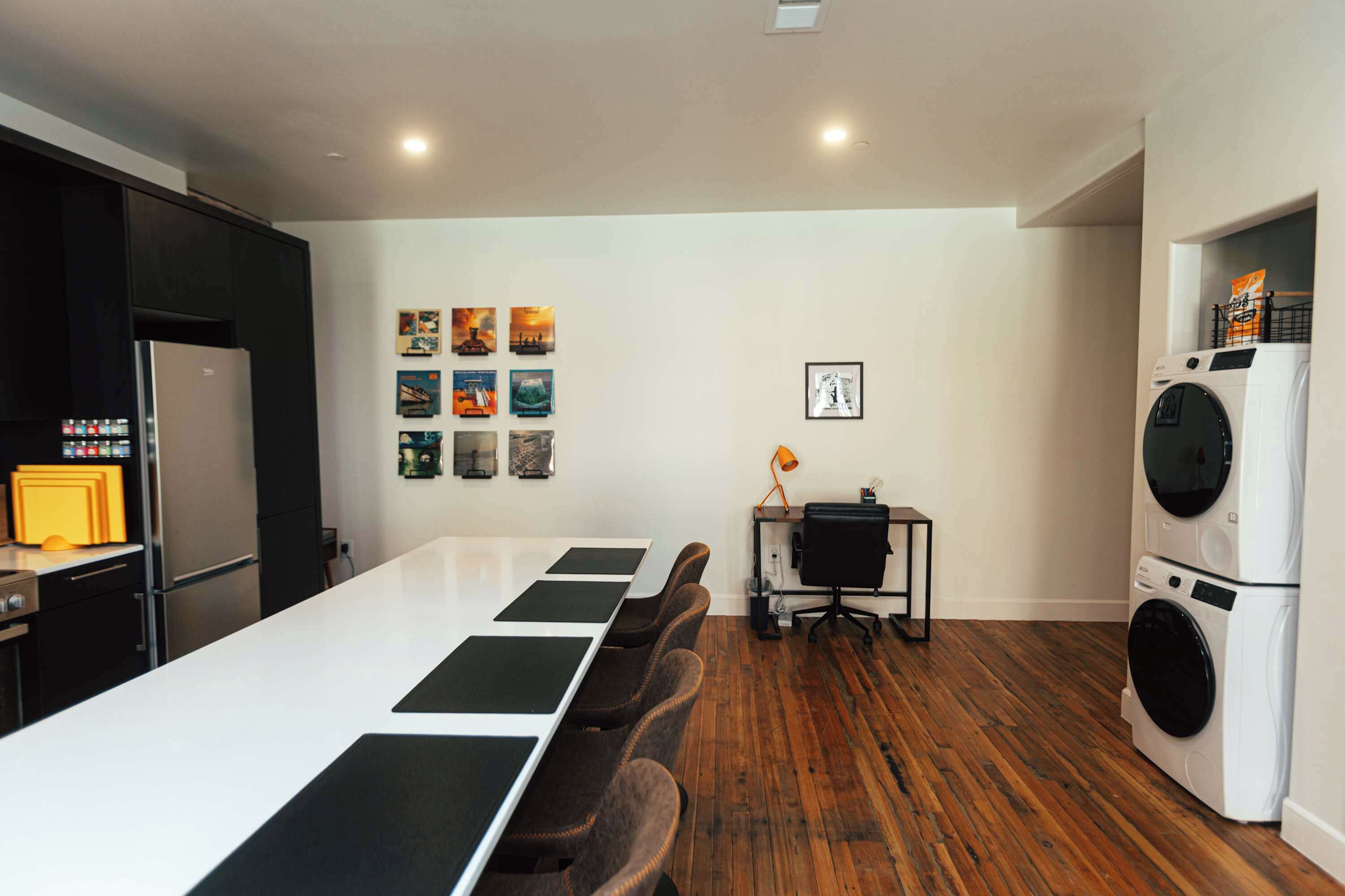 Una cocina moderna con una mesa larga de comedor, un refrigerador y una lavadora.