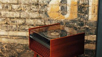 Tocadiscos antiguo sobre un soporte de madera frente a una pared de ladrillo con textura.