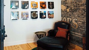 A room with a wooden floor, a green rug, a black leather chair, and a wall with framed posters. - Loft 301 The William - 3rd Ave Views - Carrigans (Birmingham)