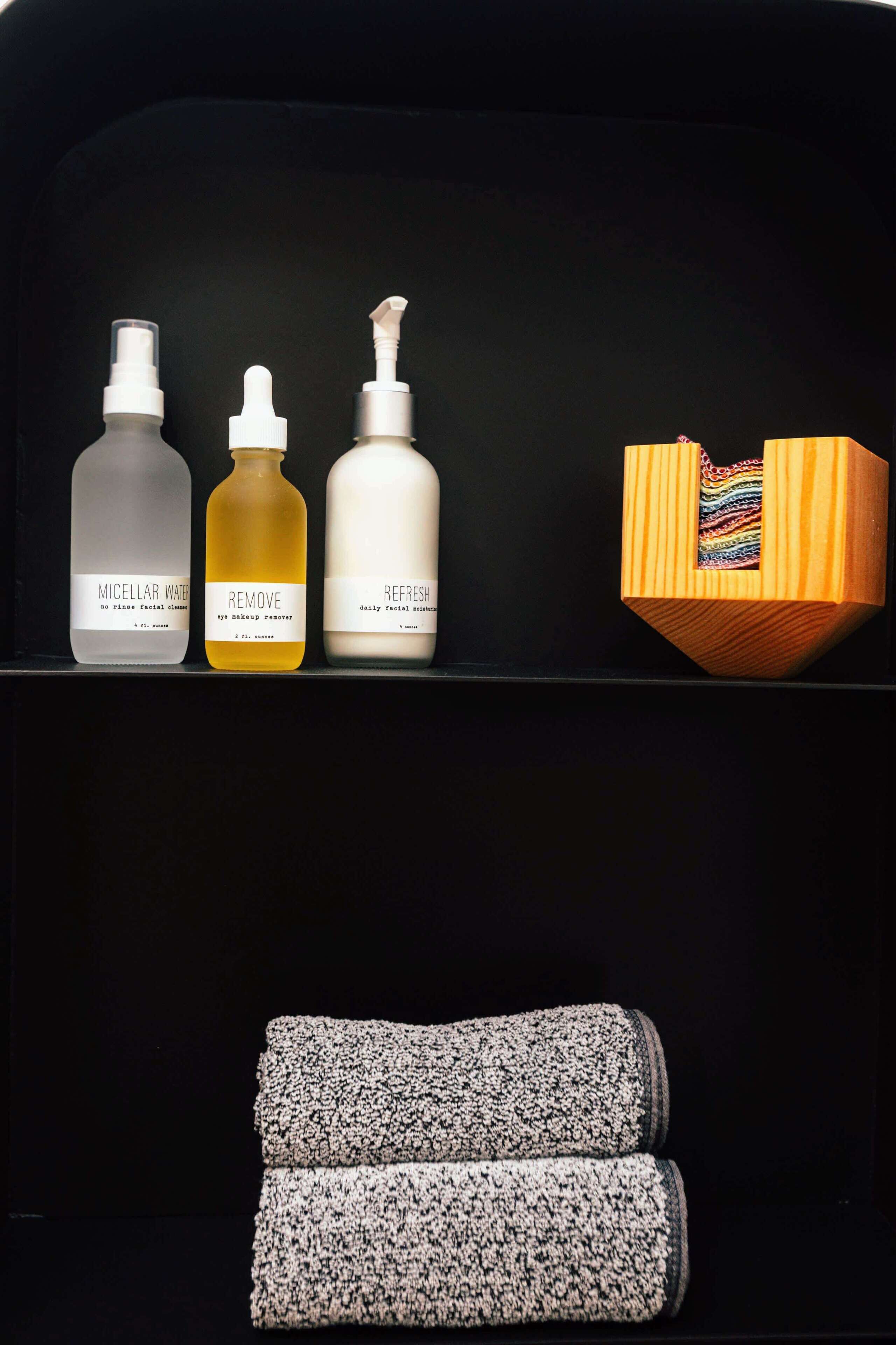 A shelf with three bottles of skincare products and a wooden box with a colorful item inside.