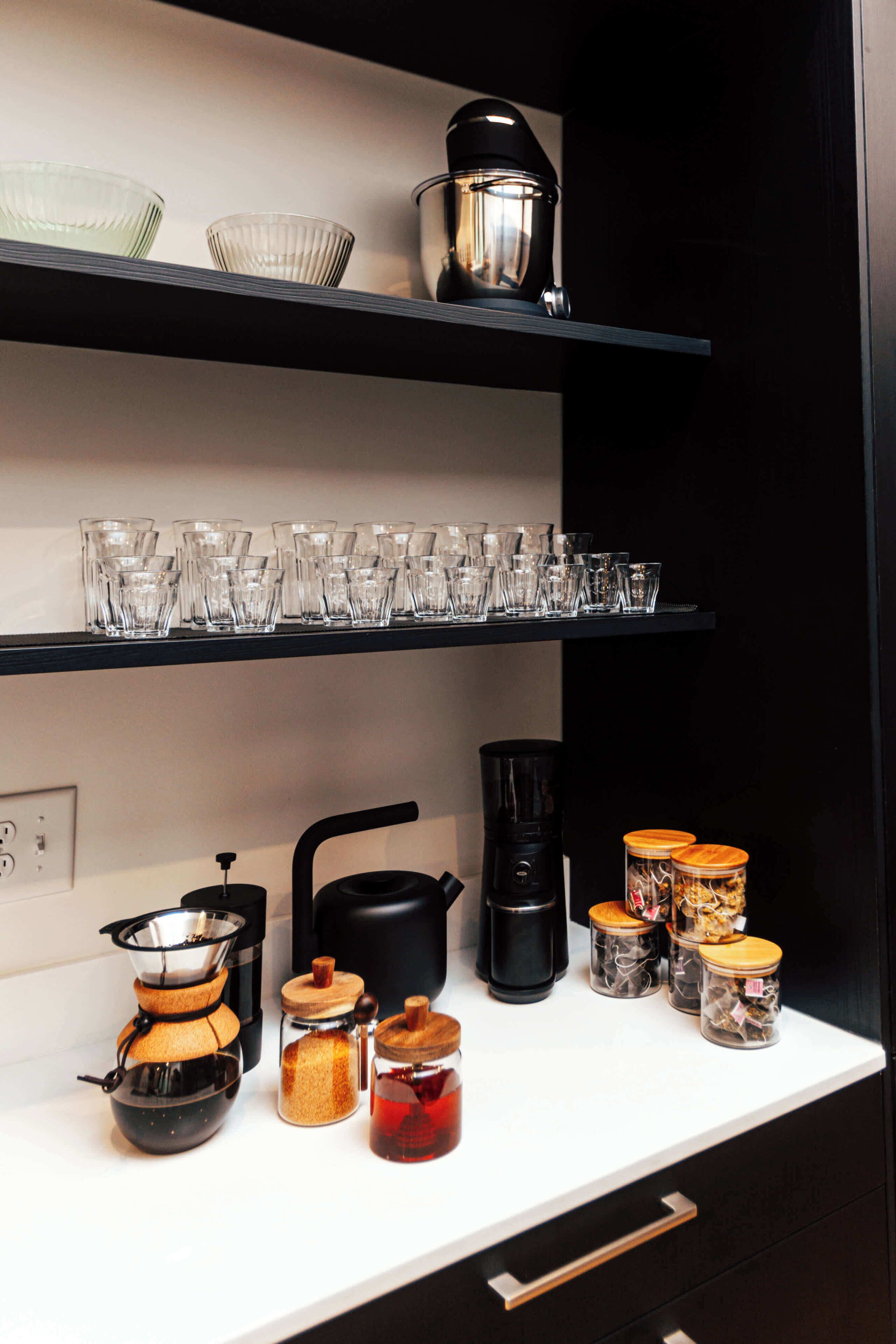 A kitchen counter with a coffee maker, a kettle, and various jars.