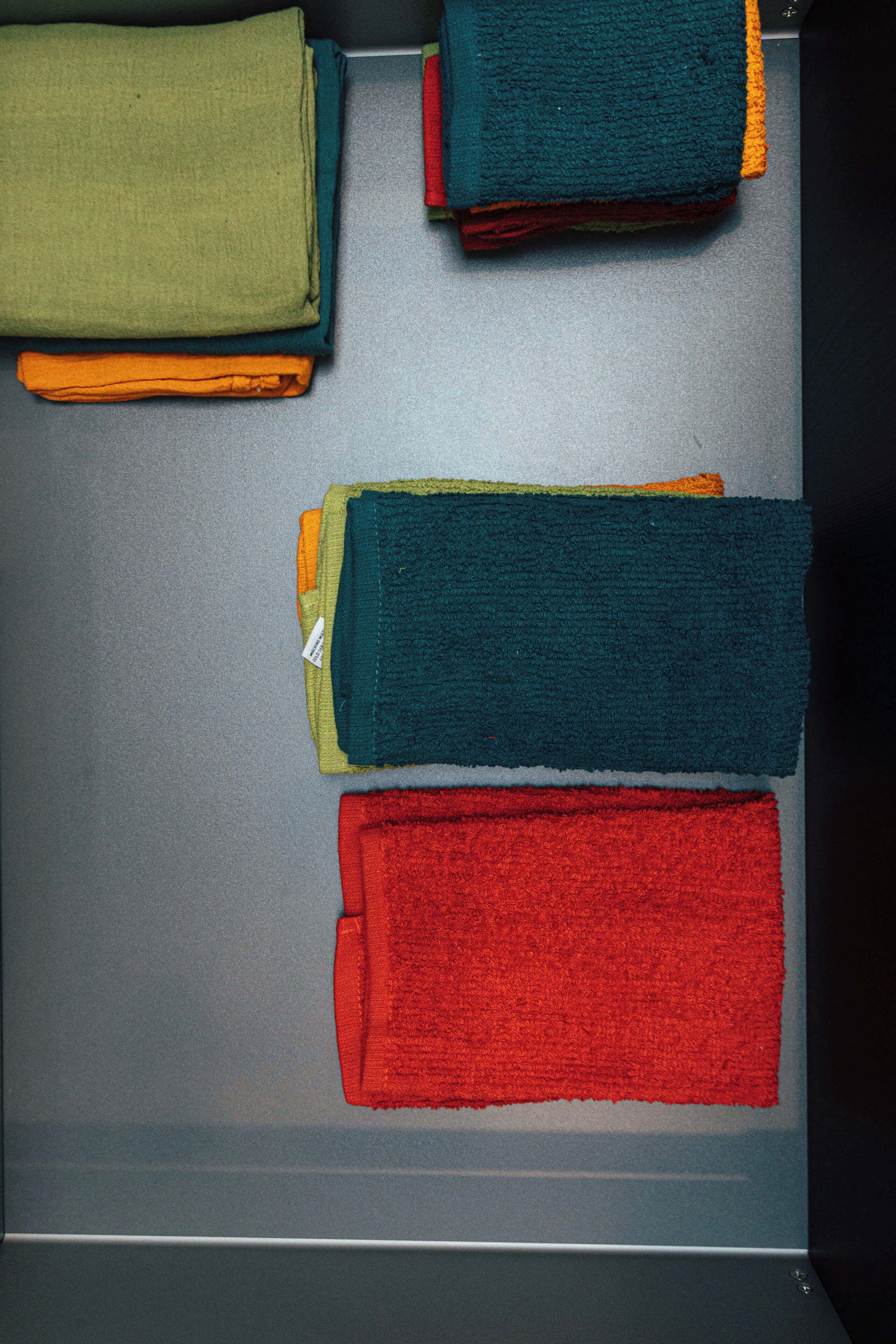 Un área de almacenamiento ordenada con toallas dobladas de varios colores.
