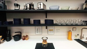 A kitchen with black shelves holding various kitchenware, a coffee maker, and a kettle. - Loft 305 - The William - Atrium - Live Work Walk (Birmingham)