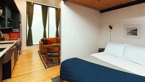 A room with a bed, a sofa, a small table, and a kitchen area. - Loft 305 - The William - Atrium - Live Work Walk (Birmingham)