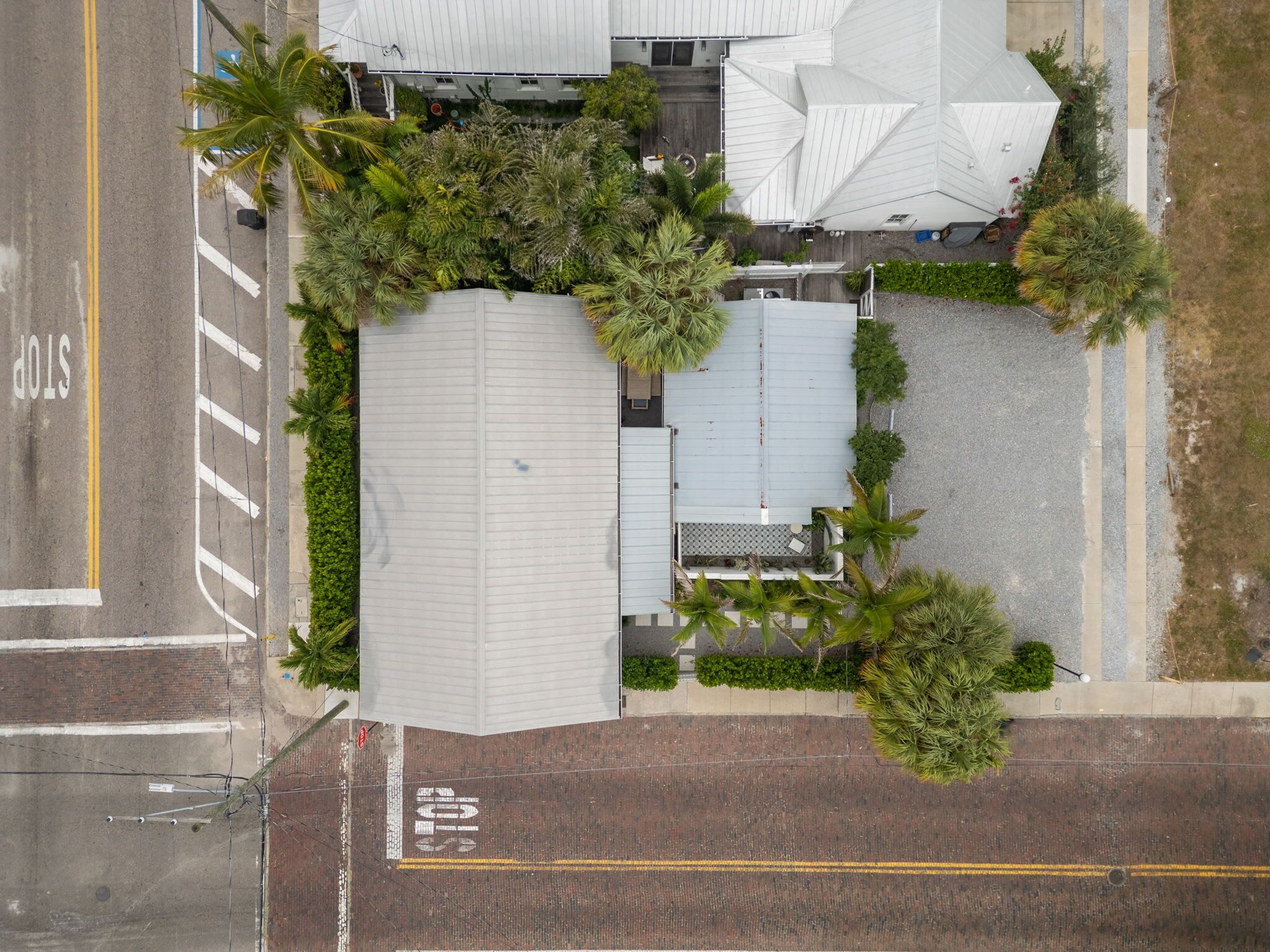 An aerial view of a building with a flat roof, surrounded by palm trees and a parking lot.