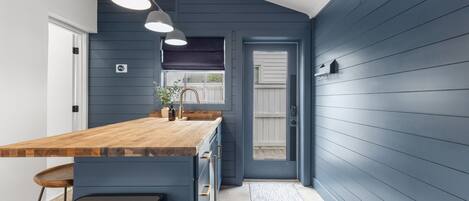 A modern kitchen with a wooden countertop, built-in appliances, and pendant lighting.